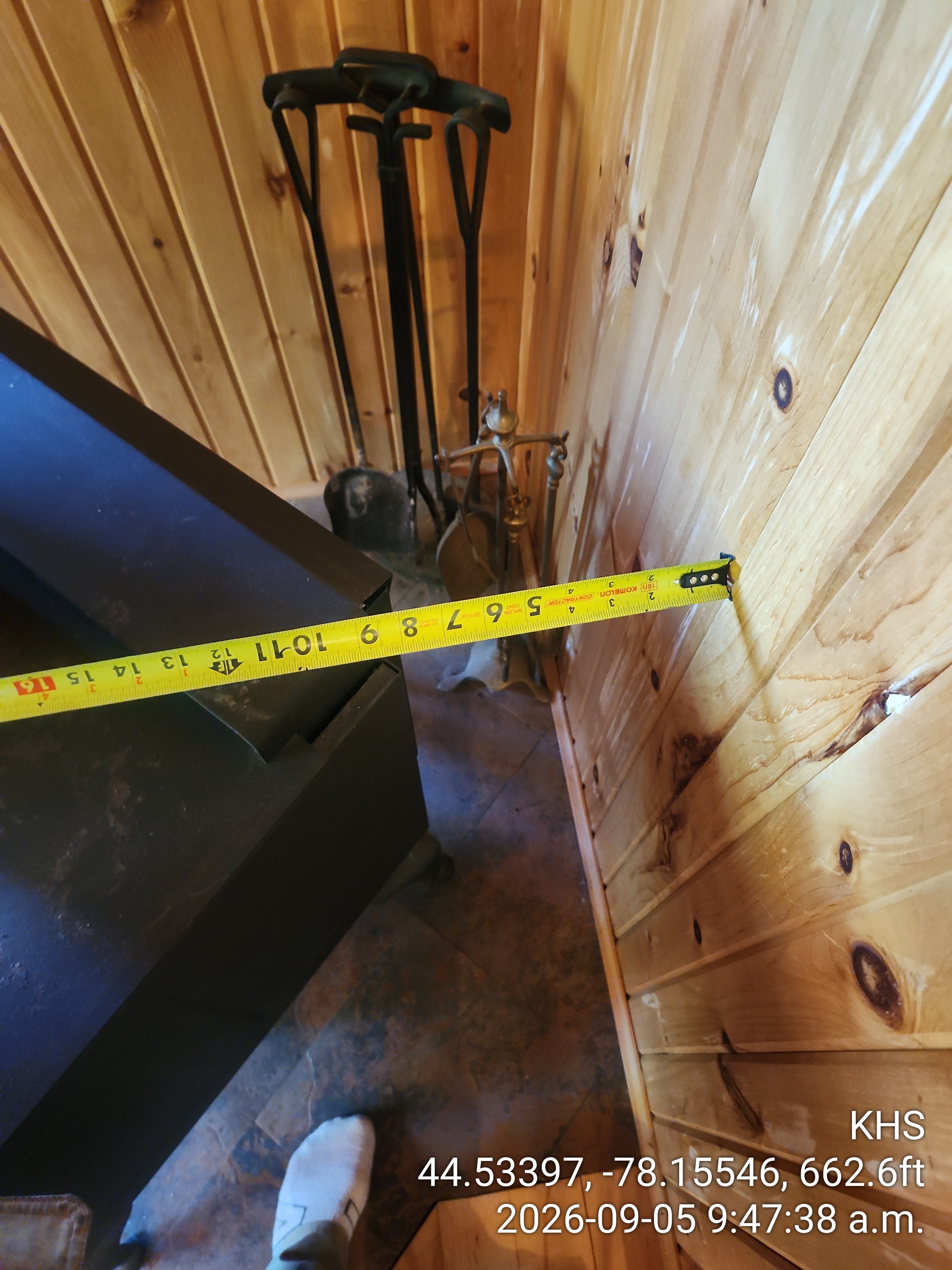 Proper clearances prevent the ignition of nearby combustible materials during operation. A wood burning stove installed on a non-combustible tile hearth with significant distance from the wall.