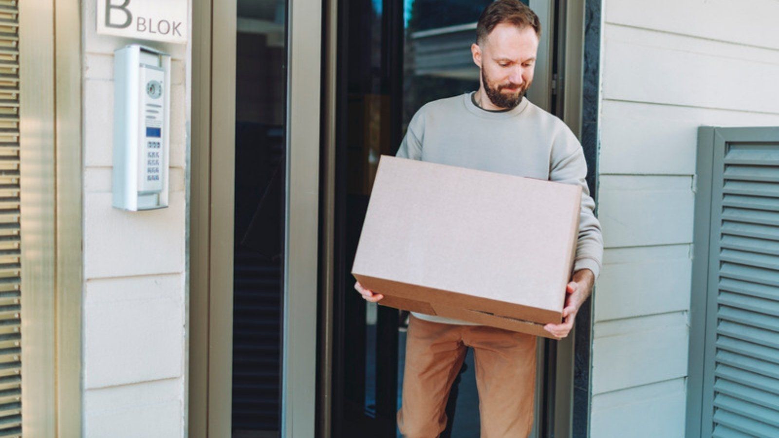 Man receiving a parcel at the door, the kind of delivery that fake parcel delivery text scams copy in the UK