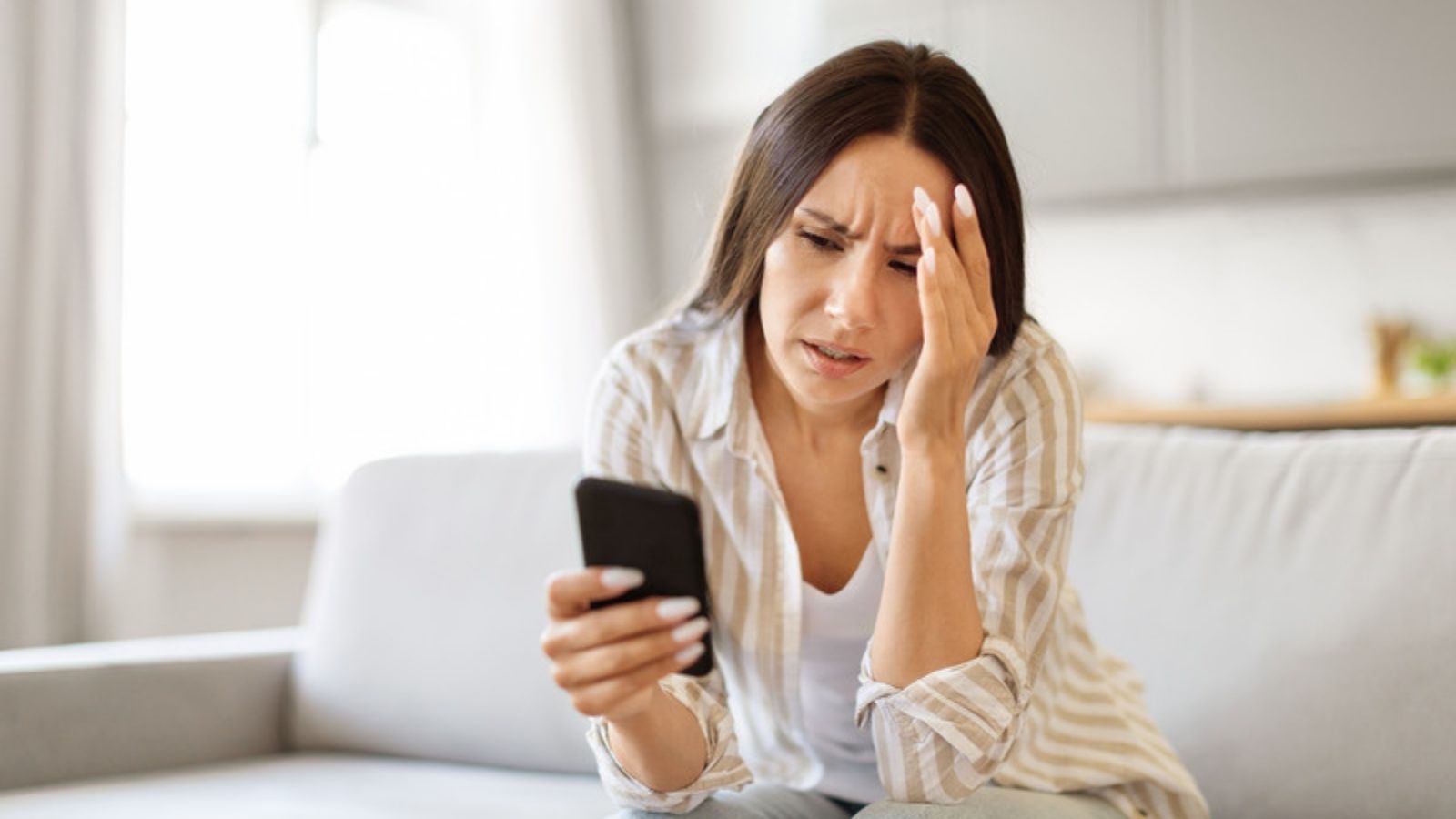 Worried woman looking at a suspicious message on her phone, The Email Security Habits That Keep Scams Out of My Inbox