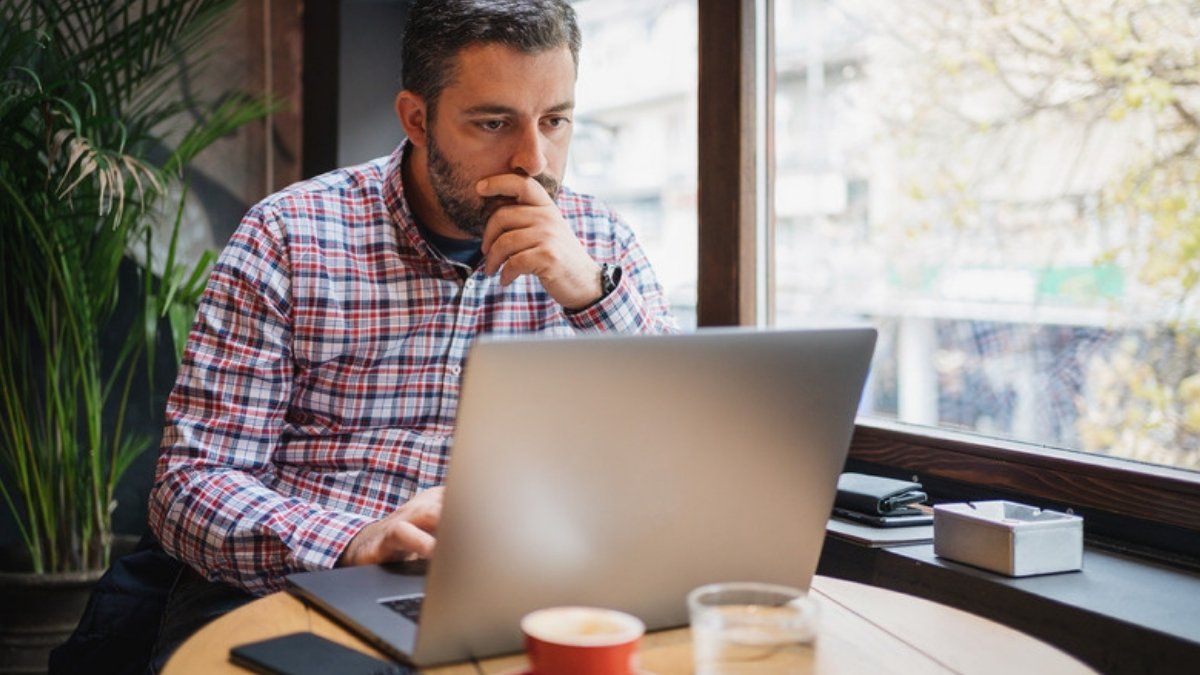 Man frowning at his laptop while checking a suspicious email, one of the phishing myths people still believe