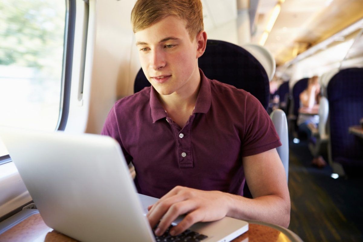 VPN settings to change from default: man using a laptop on a train