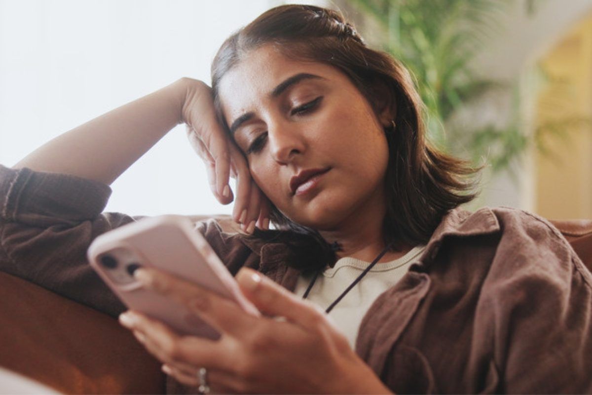 How to stay safe on social media: woman scrolling her phone at home