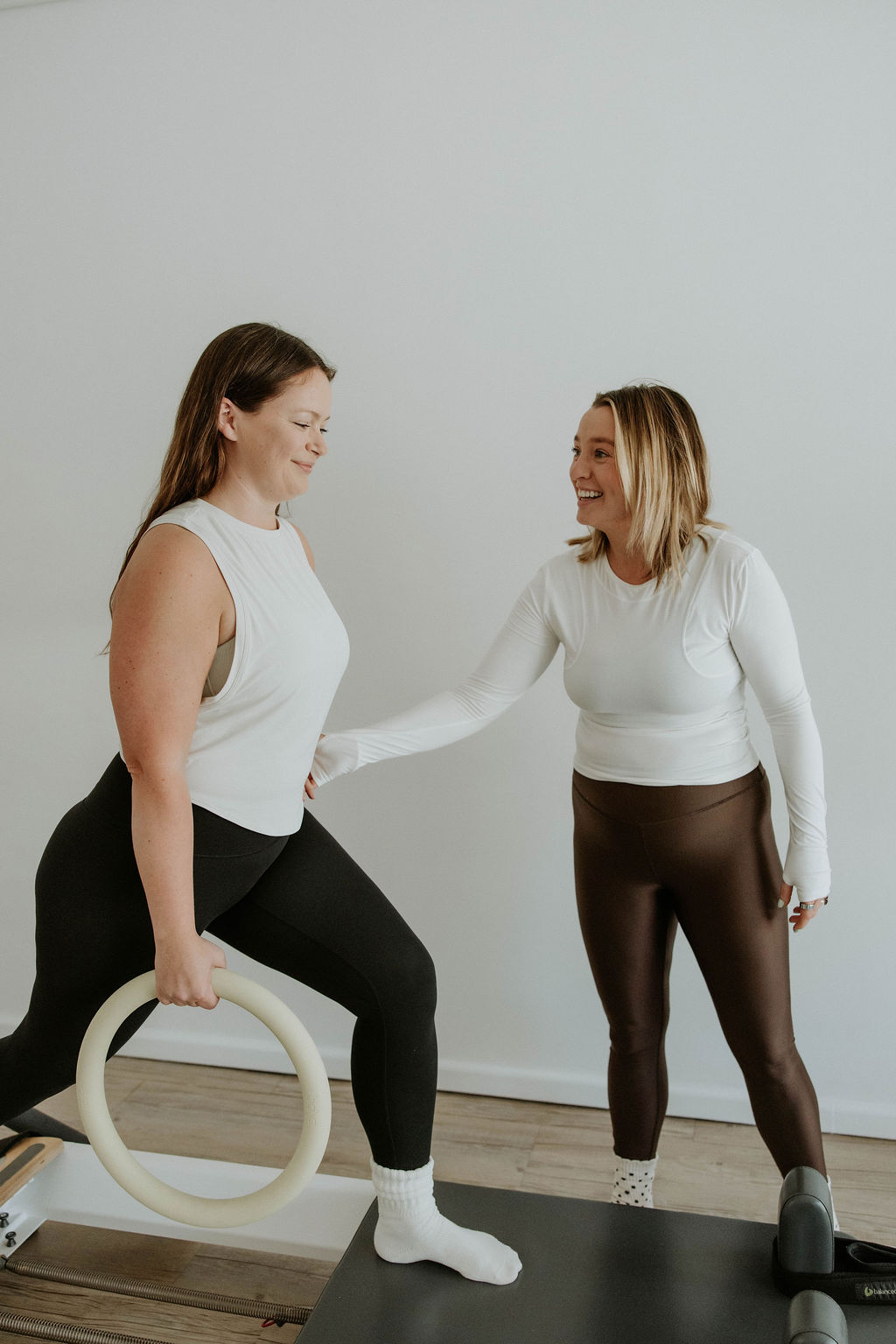 Individualized attention ensures that every movement is safe and effective for your bone health. A Pilates instructor standing beside a client during a private session ensuring proper posture and alignment.