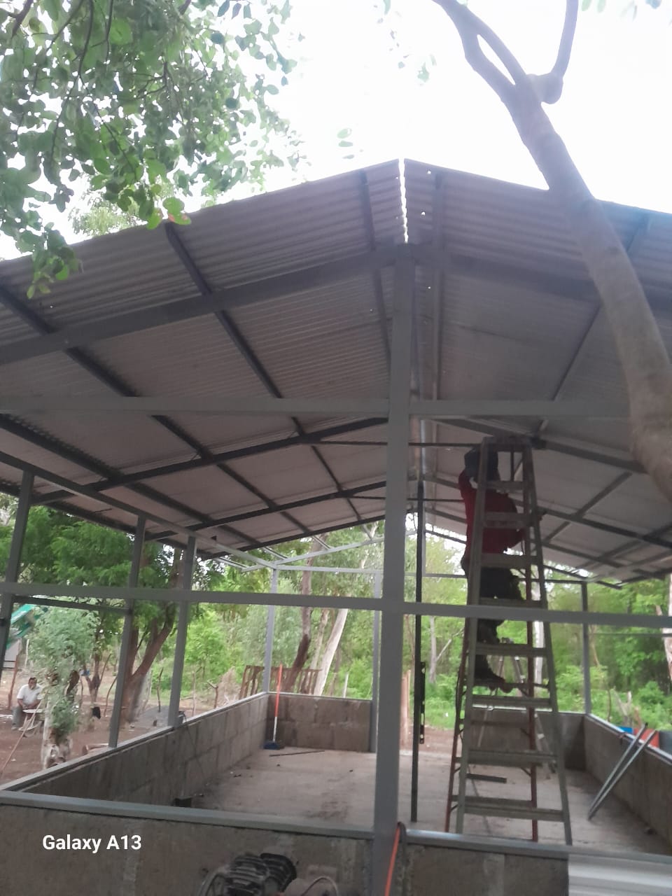 Trabajador en escalera instalando láminas de metal en el techo