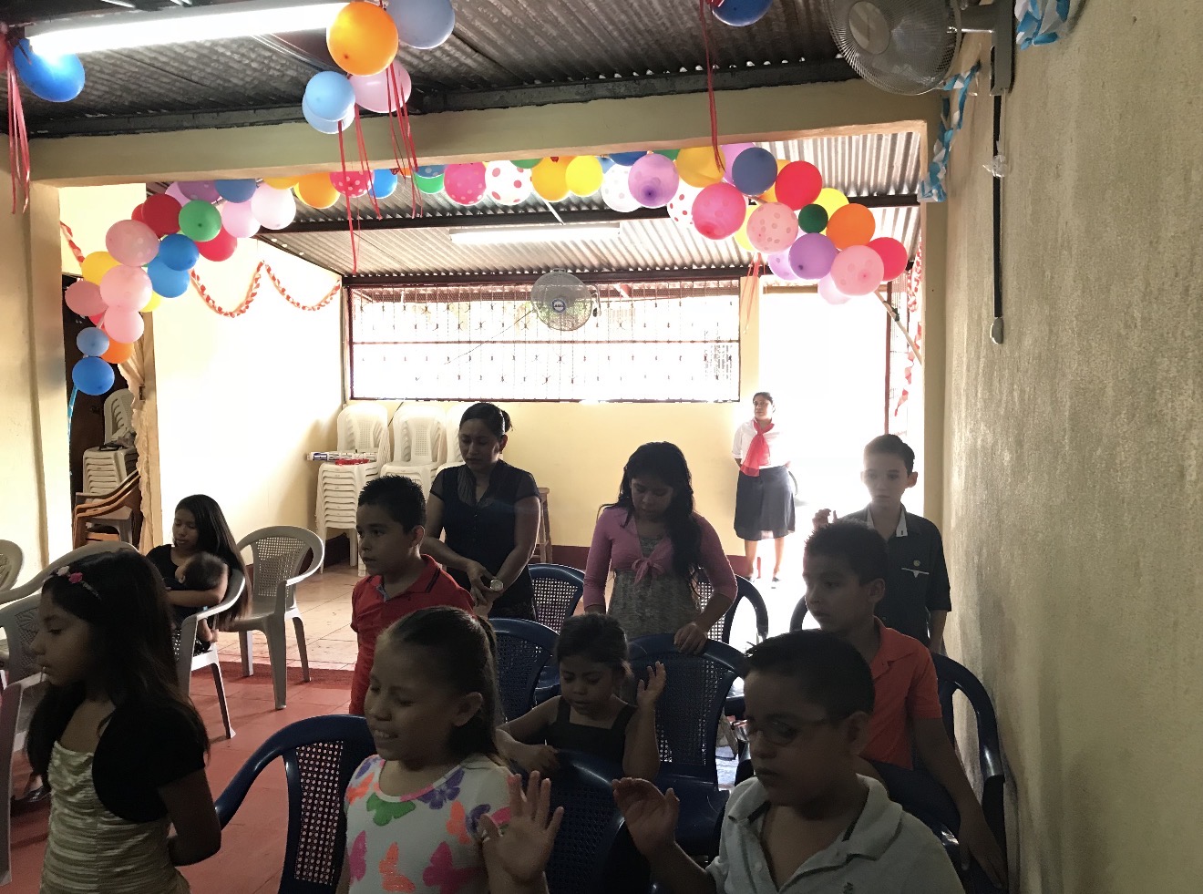Niños sentados en sillas azules en una habitación decorada con globos
