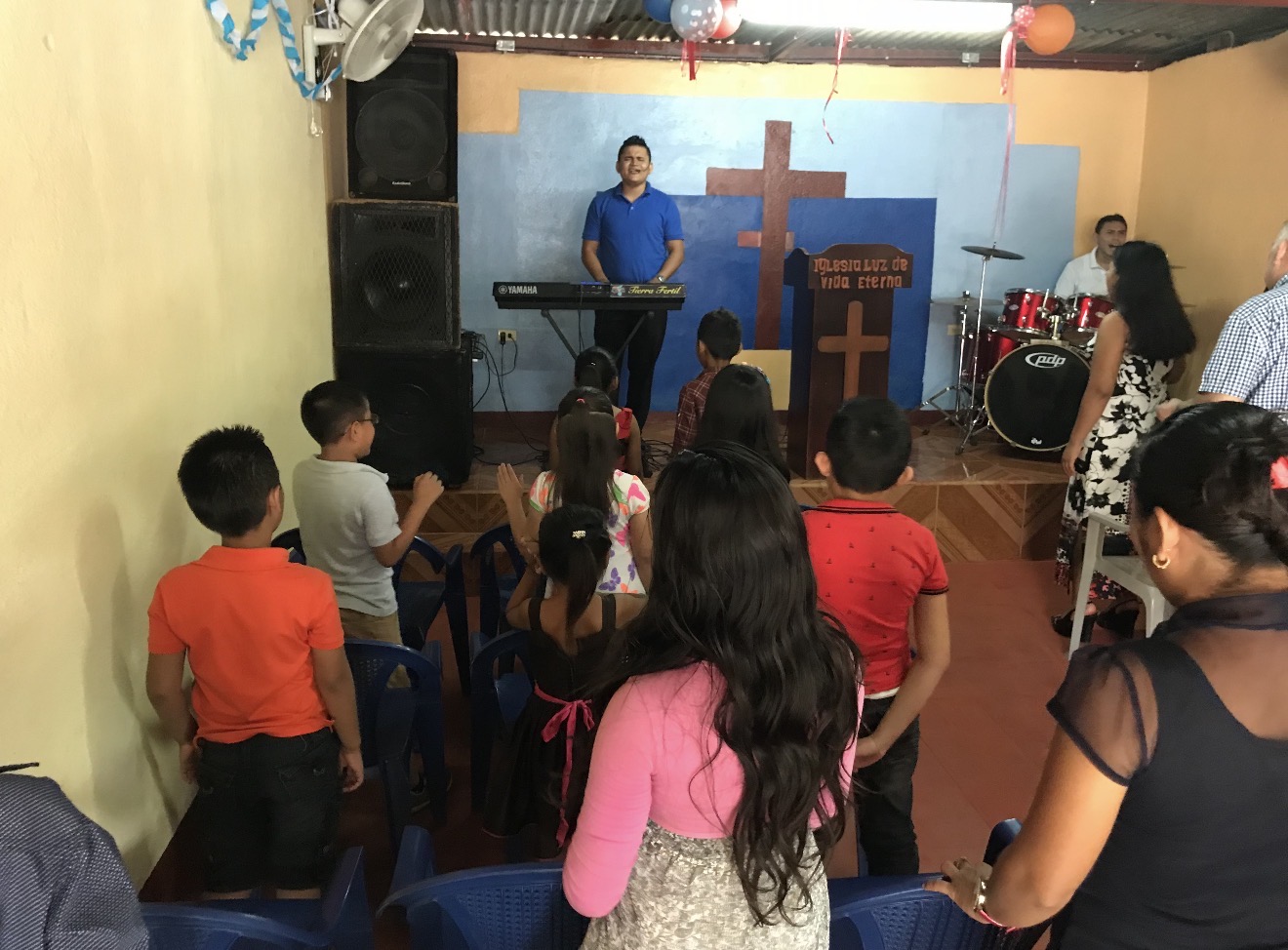 Niños y adultos en la iglesia durante la alabanza