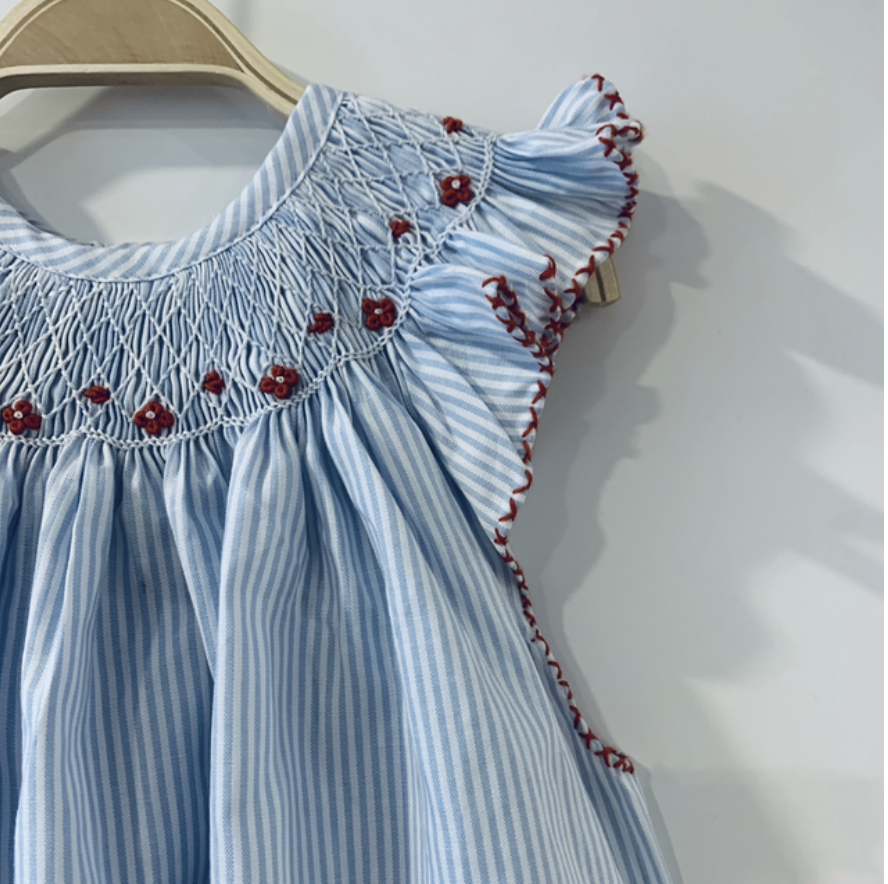 The journey of an heirloom piece begins with the skilled hands of Parisian artisans. Parisian artisan's hands carefully folding white cotton voile on a wooden workshop table.