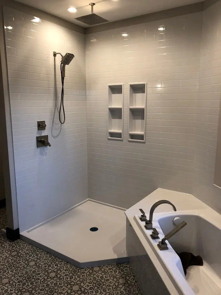 Professional waterproofing is a critical labor cost that ensures the longevity of your remodel. Orange Schluter KERDI waterproofing membrane being installed on a shower wall by a professional.