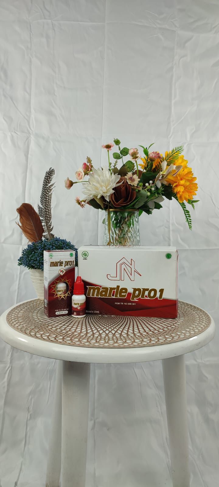 Kemasan Marie Pro1 di atas meja putih bundar dengan latar belakang bunga.