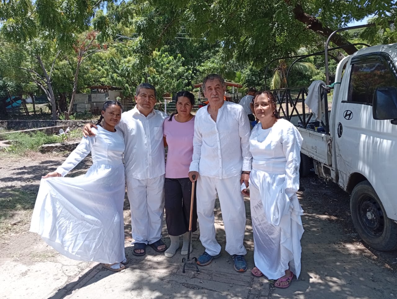 Cinco personas posan juntas, cuatro vestidas de blanco