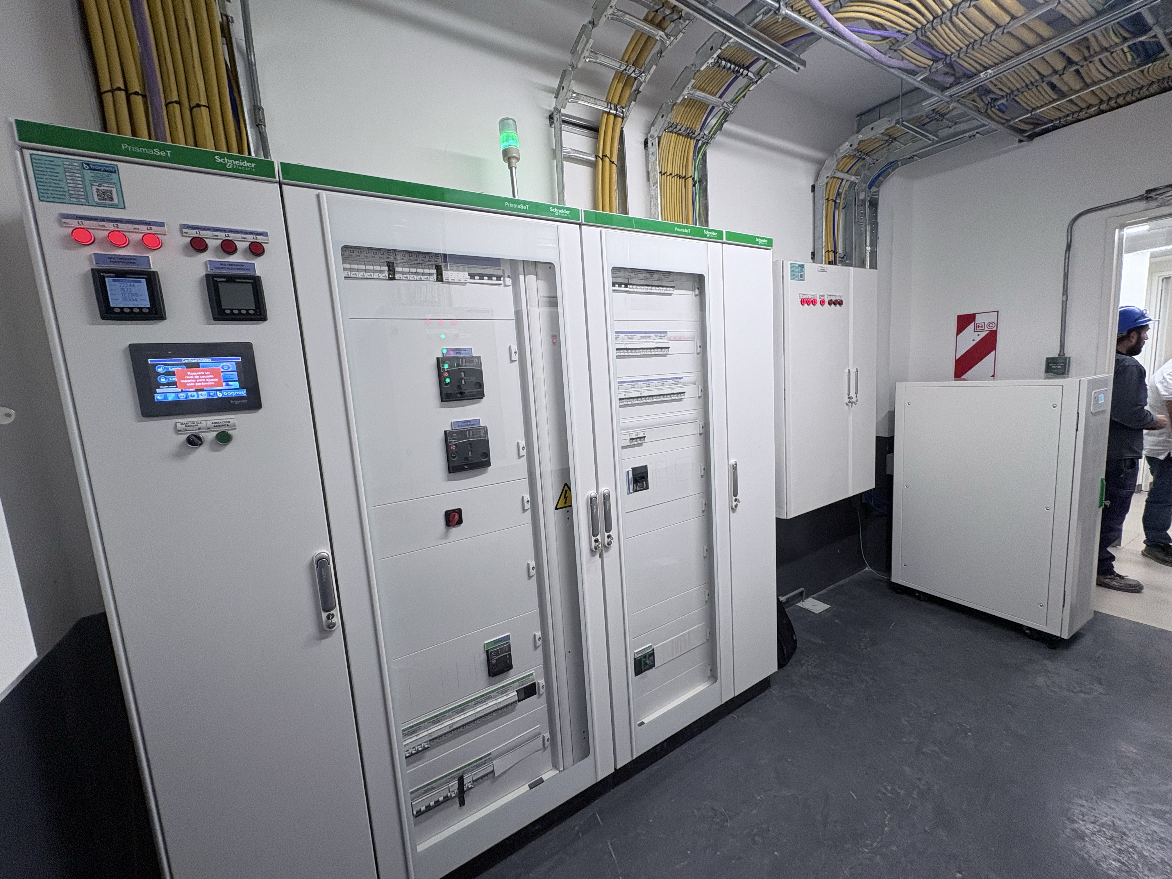 Armarios de control eléctrico PrismaSeT con indicadores luminosos y bandejas de cables en el techo.